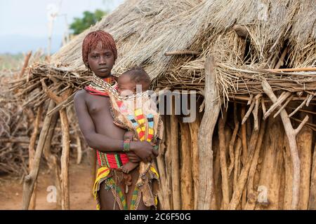 Junge schwarze Mädchen mit Baby des Stammes Hamar / Hamer in Dorf im Omo River Valley, Debub Omo Zone, Süd-Äthiopien, Afrika Stockfoto