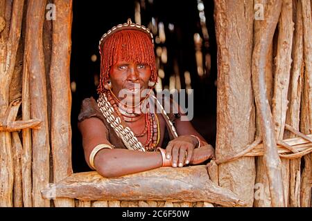 Alte schwarze Frau des Stammes Hamar / Hamer Blick durch Fenster in Dorf im Omo River Valley, Debub Omo Zone, Süd-Äthiopien, Afrika Stockfoto