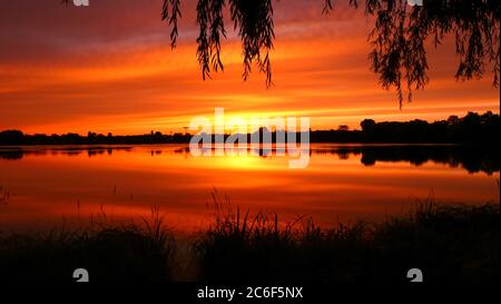 Symmetrie des Himmels in einem See bei Sonnenaufgang. Wolken, die sich auf dem Wasser spiegeln. Ferienlandschaft am Meer. Ruhige entspannende Szene mit einem schönen bunten Stockfoto