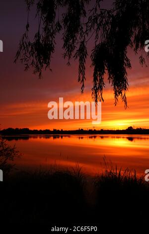 Symmetrie des Himmels in einem See bei Sonnenaufgang. Wolken, die sich auf dem Wasser spiegeln. Ferienlandschaft am Meer. Ruhige entspannende Szene mit einem schönen bunten Stockfoto