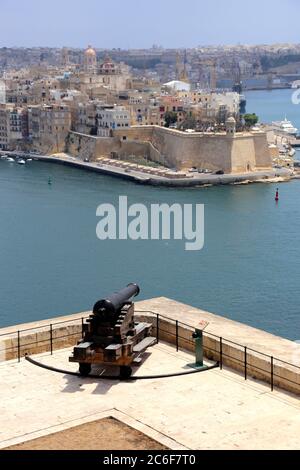 Valletta. Malta. Altstadt. Blick über den Grand Harbour von Senglea mit der Festung Spur am Ende der Halbinsel. Die Kanone bei Saluting Battery. Stockfoto