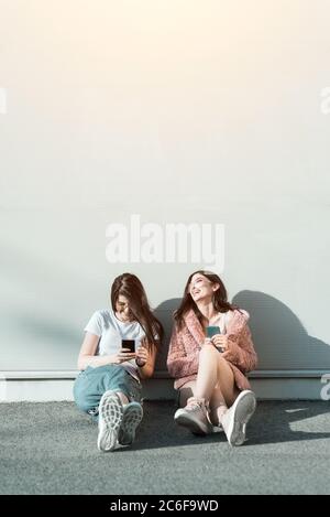 Zwei junge Freundinnen, die Handys benutzen und lachen Stockfoto