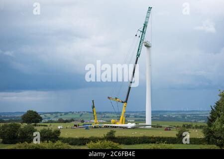 Larkhall, Schottland, Großbritannien. Juli 2020. Im Bild: Eine riesige Windkraftanlage steht ein paar hundert Meter hoch, während ihre Klingen auf dem Boden liegen bereit, befestigt werden. Grüne Energie ist ein großes Geschäft, und wenn Großbritannien seine Ziele für erneuerbare Energien archivieren soll, müssen mehr Windenergieanlagen an Land und auf See gebaut werden. Quelle: Colin Fisher/Alamy Live News Stockfoto