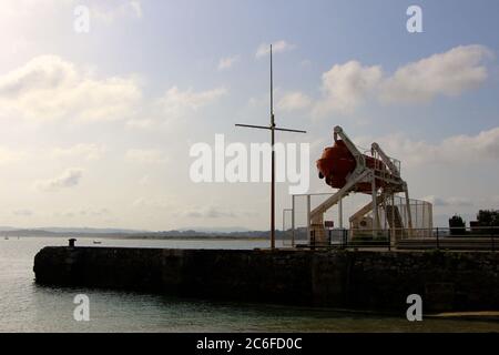 Leuchtend orange stillgelegte Kapsel Leben Boot in einem weißen Startrahmen neben der Bucht in Santander Cantabria Spanien aufgehängt Stockfoto