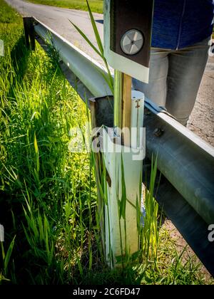 Kreative Geocaching Container versteckt sich hinter einer Crash-Barriere Stockfoto