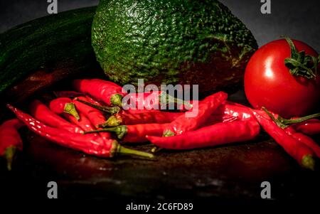 Nahaufnahme einer Variation von frischem Gemüse in einer Gruppe im Sonnenlicht mit Kopierraum am Boden, Tomaten, Chili, Avocado und Zucchini Stockfoto