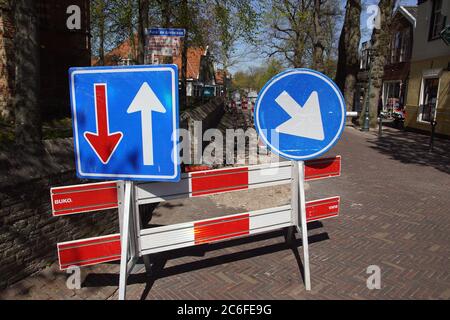 Gebrochene Straße im niederländischen Dorf Bergen, mit Verkehrsschildern, die anzeigen, wer Wegrecht hat und auf welcher Seite Sie passieren müssen. Stockfoto