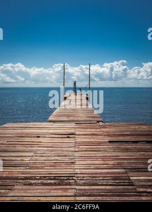 Verlorene Landestelle mit verwitterten Planken reicht direkt in das marineblaue karibische Meer Stockfoto