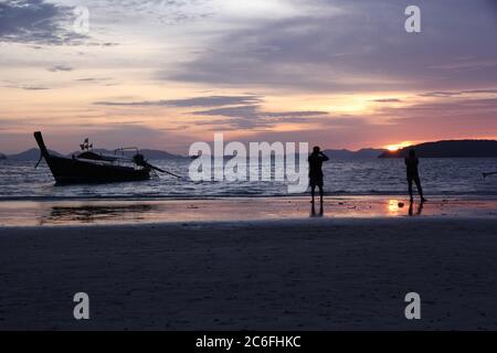 Die Menschen haben beim Fotografieren des farbenfrohen Sonnenuntergangs über der Andamanensee von Railay Beach, Krabi, Thailand, einen Silhouettenriss gemacht Stockfoto