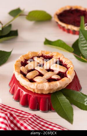 Offener Kuchen aus Mürbeteig mit Kirschen und Himbeeren, ein Kuchen mit Serviette auf weißem Hintergrund Stockfoto