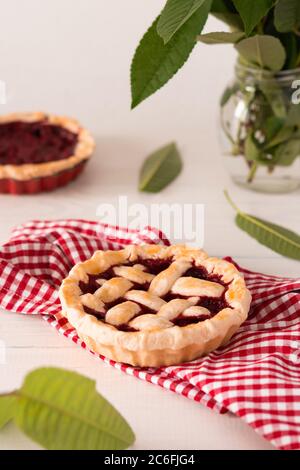 Offener Kuchen aus Mürbeteig mit Kirschen und Himbeeren, ein Kuchen mit Serviette auf weißem Hintergrund Stockfoto