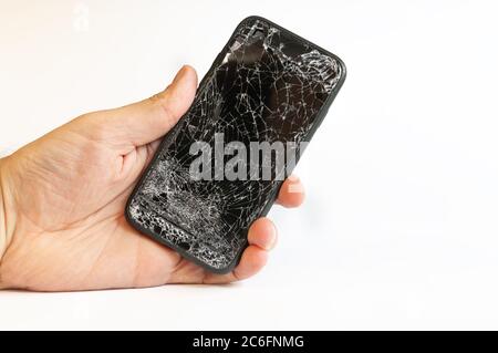 Modernes Smartphone mit stark gebrochenen Bildschirm in Männer Hand auf weißem Hintergrund Stockfoto