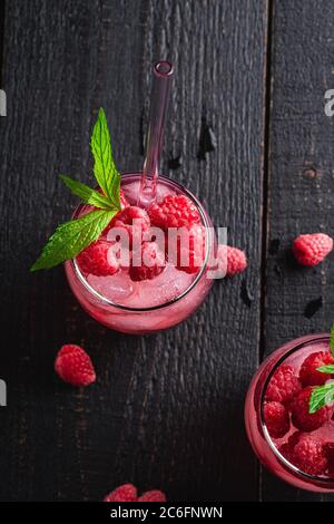 Frisch eiskalter Beerensaft-Drink mit Minze, Sommerlimonade in zwei Gläsern mit Strohhalmen auf dunklem Holzhintergrund, Draufsicht Kopierraum Stockfoto