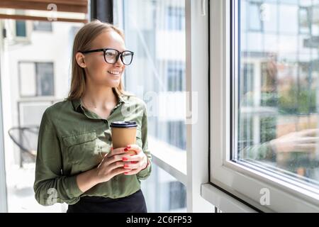 Junge Geschäftsfrau beim Kaffee trinken im Büro Stockfoto