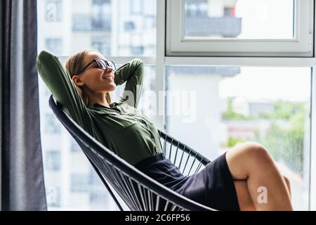 Junge Frau, die sich zu Hause im Schaukelstuhl ausruht Stockfoto