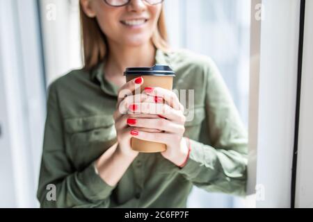 Junge Geschäftsfrau beim Kaffee trinken im Büro Stockfoto