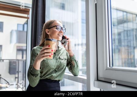 Junge Frau ruft mit dem Handy an, während sie in der Freizeit allein im Café sitzt. Stockfoto