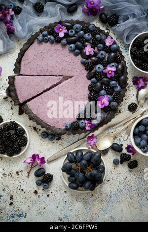 Süße und leckere Tarte mit frischen Heidelbeeren, Brombeeren und Trauben, serviert auf steinernem Hintergrund Stockfoto