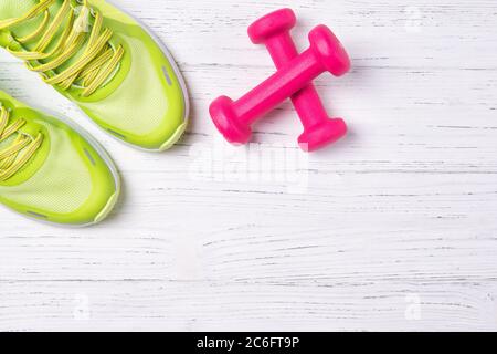 Fitnesskonzept, grüne Sneaker und rosa Hanteln auf Holzhintergrund, Draufsicht mit Kopierfläche Stockfoto
