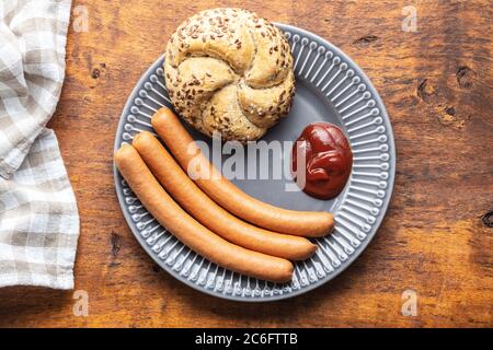 Frische frankfurter Würstchen mit Brötchen und Ketchup auf dem Teller. Draufsicht. Stockfoto