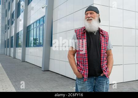 Erfahrener älterer Mann mit Bart auf der Straße posiert und lächelt, Porträt Stockfoto