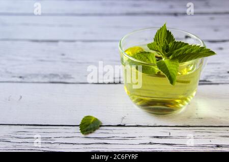 Frisches Minztee-Konzept auf Holzhintergrund. Minztee in einer Tasse, Stockfoto