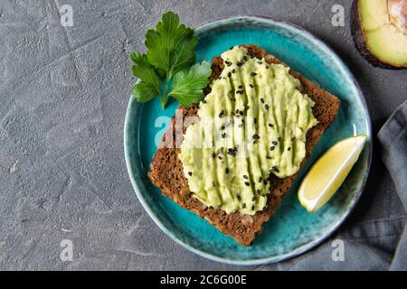 Avocado Toast auf Vollkornbrot, Avocado-Püree mit Sesamsamen und Limette, gesundes Esskonzept, Draufsicht Stockfoto