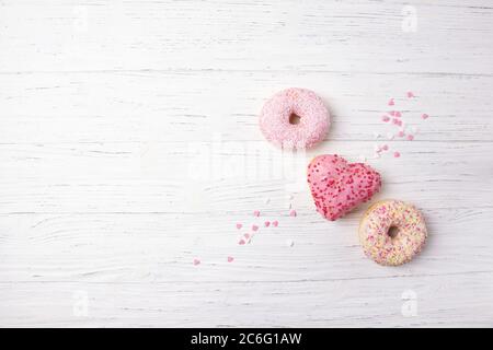 Donuts in Herzform auf Holzhintergrund, Draufsicht Stockfoto