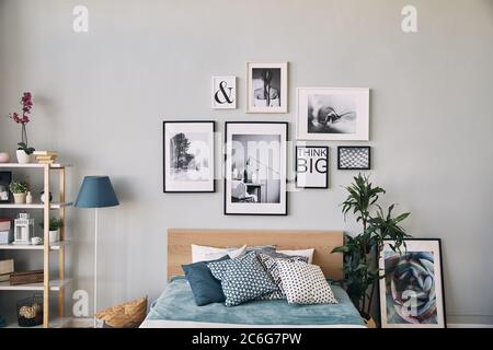 Fotos in verschiedenen Größen in einem Rahmen über dem Bett hängen. Moderne Schlafzimmer. Stockfoto