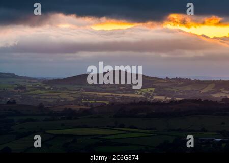 Askerswell, Dorset, Großbritannien. Juli 2020. Wetter in Großbritannien. Blick vom Eggardon Hill bei Askerswell in Dorset Blick auf Lewesdon Hill als Pause in der dunklen launischen Wolken leuchten orange bei Sonnenuntergang. Bildquelle: Graham Hunt/Alamy Live News Stockfoto