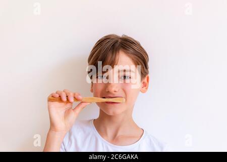 Schönes Mädchen Kind putzt ihre Zähne mit hölzernen Zahnbürste vor weißem Hintergrund. Gesundheitswesen, Zero Waste Konzept. Stockfoto