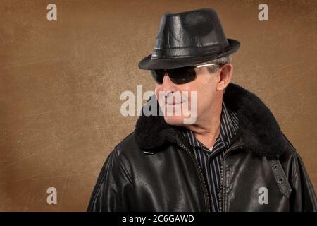 Älterer Mann mit Lederhut, Jacke und Sonnenbrille Stockfoto