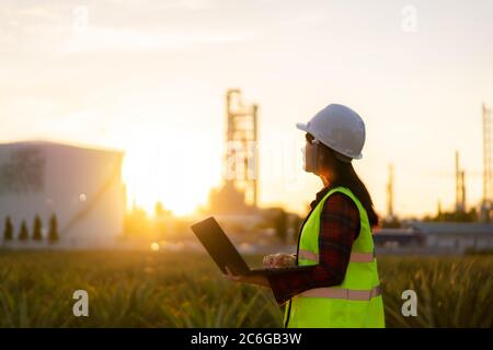 Asiatische Frau petrochemische Ingenieur arbeiten in der Nacht mit Laptop in Öl-und Gas-Raffinerie-Fabrik in der Industrie in der Nacht für Inspektor Sicherheit quali Stockfoto