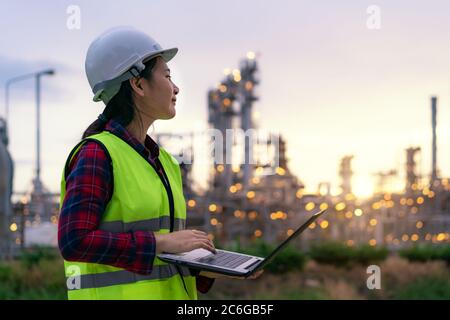 Asiatische Frau petrochemische Ingenieur arbeiten in der Nacht mit Laptop in Öl-und Gas-Raffinerie-Fabrik in der Industrie in der Nacht für Inspektor Sicherheit quali Stockfoto