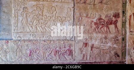 Relief aus dem Grab von Horemheb, das eine Gruppe libyscher und nubischer Gefangener zeigt, die von Wärtern mit Knüppeln umgeben sind, während ein Schreiber einen Bericht verfasst Stockfoto