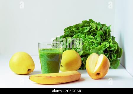 Grüner Smoothie aus Banane, Äpfeln und Salatblättern mit Zutaten, weißer Hintergrund, Nahaufnahme. Stockfoto