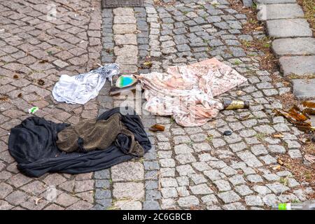 Verschmutzung - Abdeckung, T-Shirt, zerbrochene Bierflasche und Zigarrenbutts achtlos auf der Straße entsorgt. Stockfoto