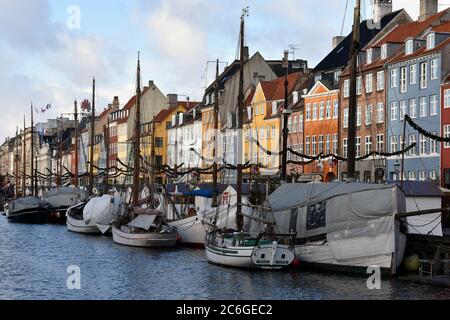 Die bunten Stadthäuser auf der Nordseite des Nyhavn Kanals. Segelboote sind entlang der Kante des Kanals gesäumt und weihnachtsdekorationen sind sichtbar. Stockfoto