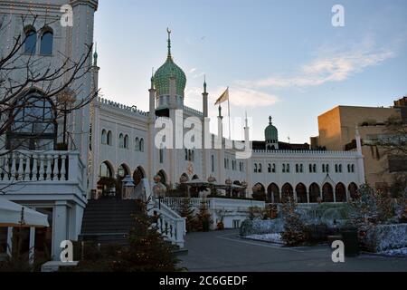The Nimb Hotel and Restaurant Wenn die Sonne in den Tivoli Gärten, Kopenhagen, Dänemark untergeht. Um das Hotel herum sind geschmückte Weihnachtsbäume zu sehen Stockfoto
