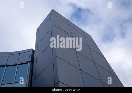 Kommerzielle Außenverbundplatten aus Metall auf einem Gebäude mit blauem Himmel und Wolken im Hintergrund. Stockfoto