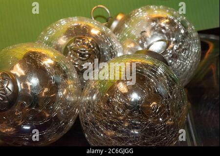 Mehrfarbige Reflexionen in glänzenden silbernen Kugeln oder Weihnachtsornamenten werden aus der Nähe betrachtet und vor einem hellgrünen Hintergrund gruppiert. Stockfoto