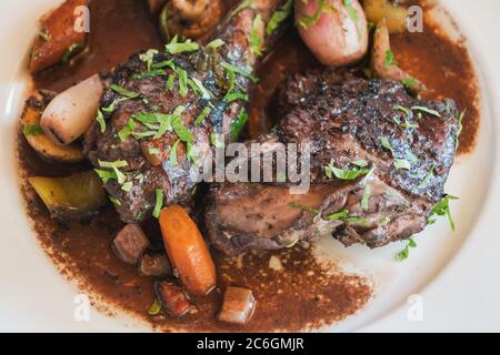 Coq au Vin, französisches Huhn in Rotwein, auf einem weißen Teller Stockfoto