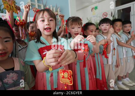 In alten chinesischen Kleidern gekleidet, tanzen Kinder in einem örtlichen Kindergarten und machen traditionelle duftende Medizintüten, um den bevorstehenden Drachen zu feiern Stockfoto