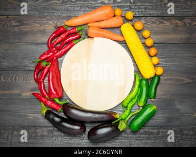 Tischanordnung mit verschiedenen frischen Früchten und Gemüse, sortiert nach Farben - Pfeffer, Tomate, Mais, Karotten, grünem Salat, Cilantro, Auberginen Stockfoto