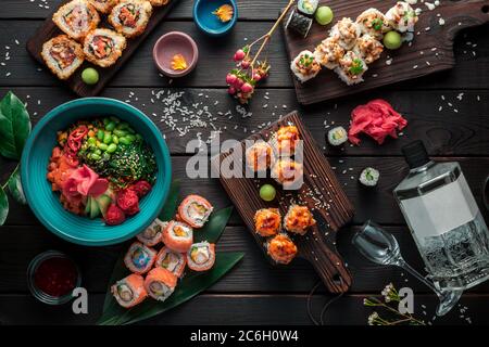 Tisch serviert mit Sushi, Brötchen und traditionellen japanischen Speisen auf dunklem Hintergrund. Draufsicht. Stockfoto