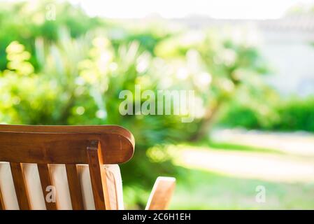 Holzstuhl auf verschwommenem Hintergrund im Garten. Abstraktes Bokeh-Licht. Sommerkonzept. Stockfoto