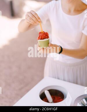 Eisverkäufer legt das Eis in die Tasse. Stockfoto