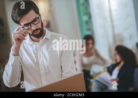 Serious junger Mann in Brille mit Laptop Stockfoto