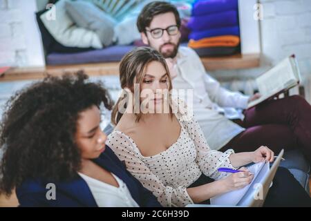 Mädchen Umschreiben von Informationen aus Laptop-Bildschirm, Freund und Freundin herum Stockfoto