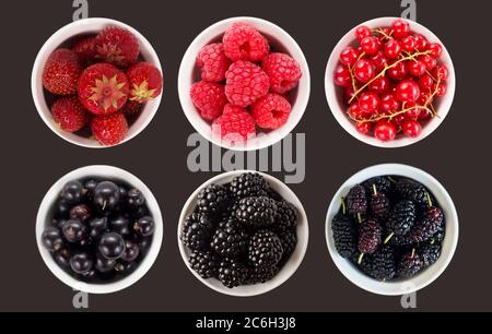 Blaue und rote Früchte und Beeren isoliert auf schwarz. Süße und saftige Beeren mit Platz für Text. Draufsicht. Maulbeeren, Brombeeren, Johannisbeere, Erdbeere Stockfoto